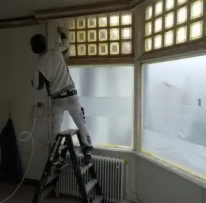 Vakman van Latex-Spuiter.nl schermt ramen af met folie en tape voor het spuiten